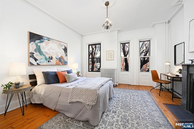 bedroom with ornamental molding, radiator heating unit, a chandelier, and wood-type flooring