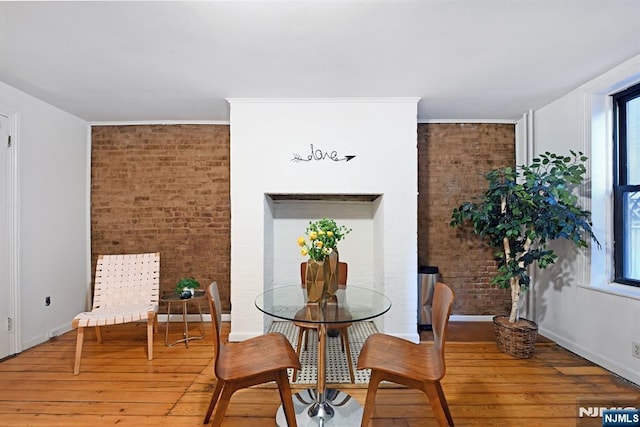 dining room featuring wood-type flooring and brick wall