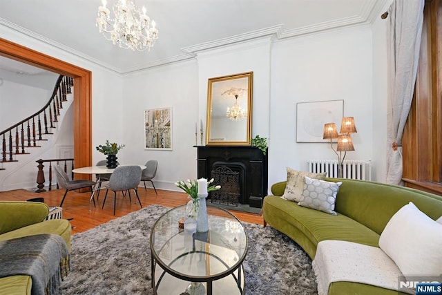 living room featuring radiator, a notable chandelier, ornamental molding, and hardwood / wood-style flooring