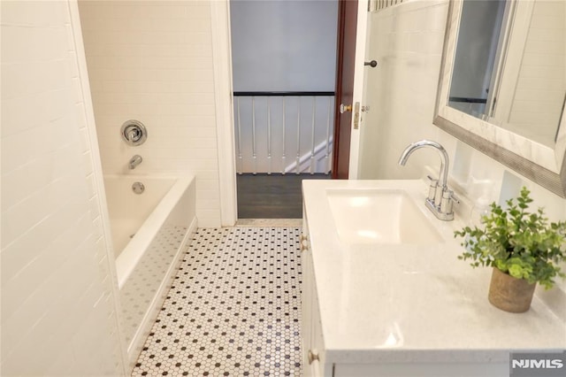 bathroom with tiled shower / bath combo, vanity, tile walls, and tile patterned floors