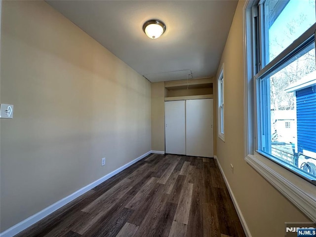 unfurnished bedroom with dark wood-type flooring and a closet