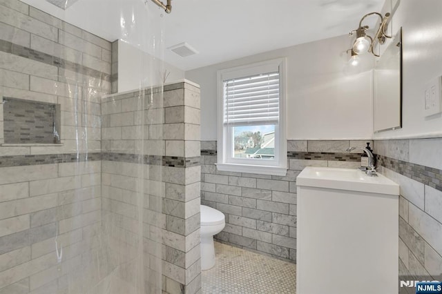 bathroom with tile walls, vanity, tile patterned flooring, and toilet