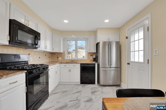 kitchen featuring tasteful backsplash, white cabinetry, sink, light stone counters, and black appliances