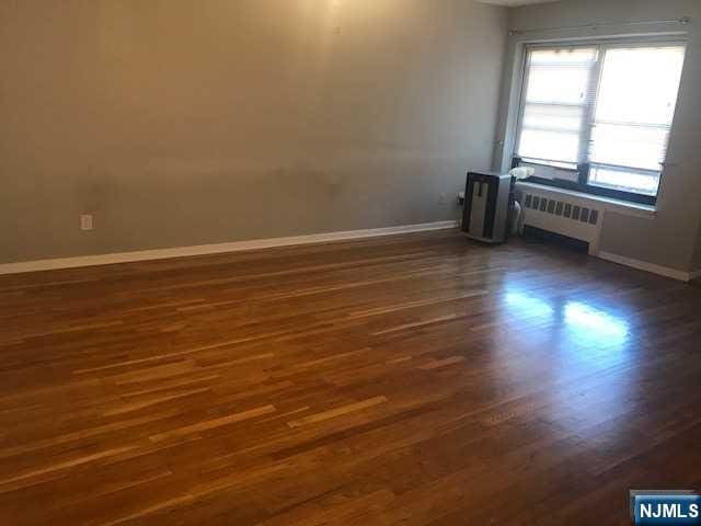 spare room with dark wood-type flooring and radiator heating unit