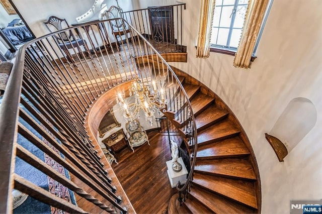 staircase featuring wood-type flooring and a chandelier