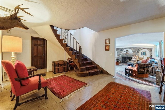 living room featuring a stone fireplace and a textured ceiling