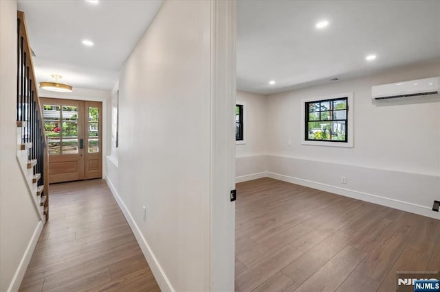 hallway with a wall mounted air conditioner, wood finished floors, baseboards, recessed lighting, and stairway