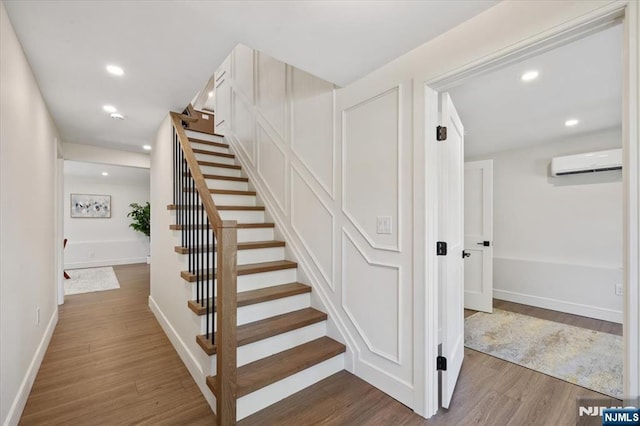 stairs featuring an AC wall unit, wood finished floors, baseboards, and recessed lighting