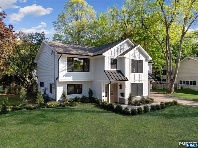 modern farmhouse style home with board and batten siding, a front lawn, driveway, and a standing seam roof