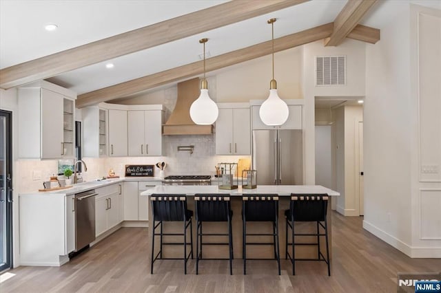 kitchen featuring appliances with stainless steel finishes, decorative backsplash, light countertops, a kitchen bar, and recessed lighting