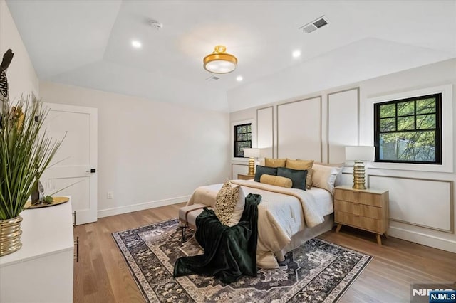 bedroom with light wood-style flooring, vaulted ceiling, and baseboards