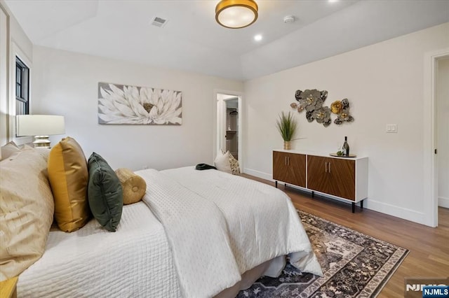 bedroom featuring wood finished floors, baseboards, and lofted ceiling