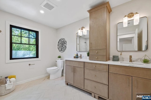 bathroom featuring toilet, double vanity, and baseboards