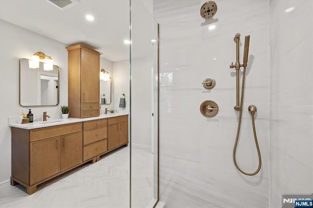 bathroom with a shower, double vanity, baseboards, and recessed lighting