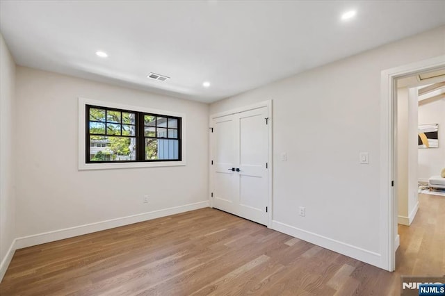 unfurnished bedroom with light wood finished floors, baseboards, recessed lighting, and a closet