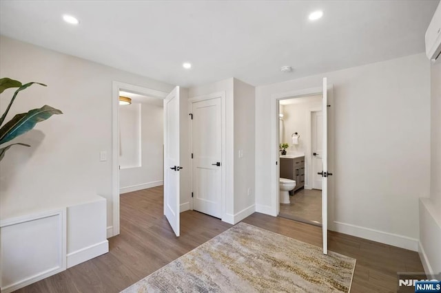 unfurnished bedroom featuring wood finished floors, baseboards, recessed lighting, and connected bathroom