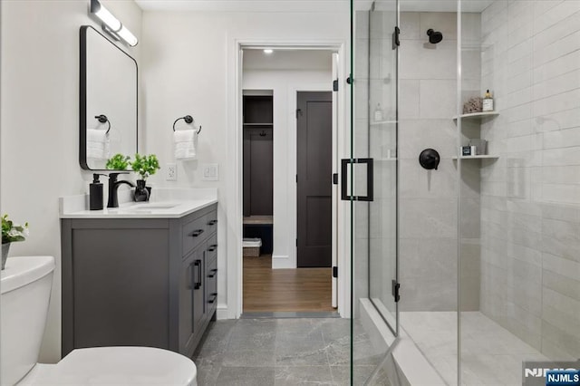 bathroom featuring toilet, tiled shower, and vanity