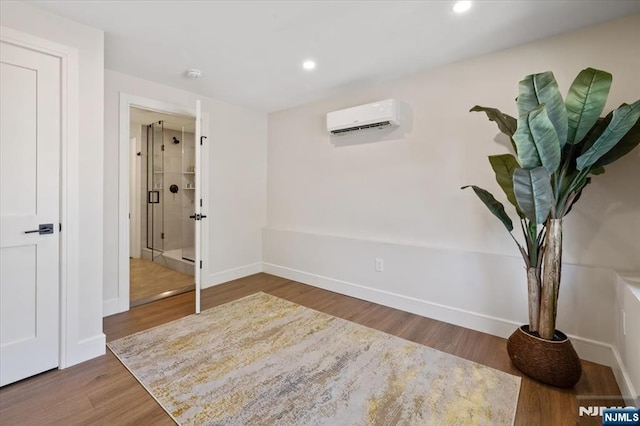 interior space featuring a wall unit AC, baseboards, wood finished floors, and recessed lighting