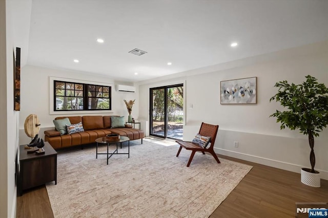 living area featuring a wall mounted air conditioner, wood finished floors, baseboards, and recessed lighting