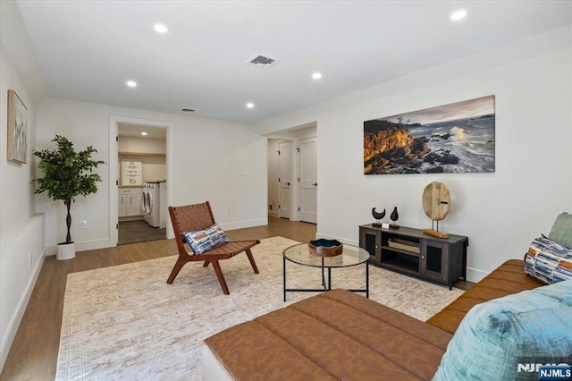 living area featuring washer and clothes dryer, recessed lighting, wood finished floors, and baseboards