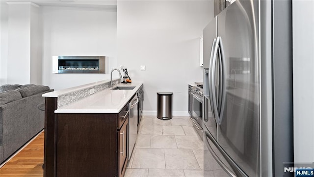 kitchen featuring dark brown cabinets, sink, and stainless steel refrigerator