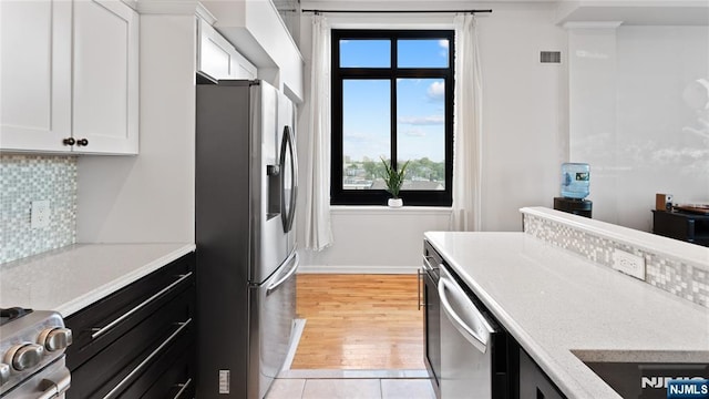 kitchen with decorative backsplash, stainless steel appliances, light hardwood / wood-style floors, and white cabinets