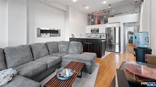 living room featuring sink, light hardwood / wood-style flooring, rail lighting, and a high ceiling