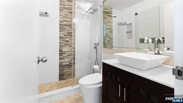 bathroom featuring tiled shower, vanity, and toilet