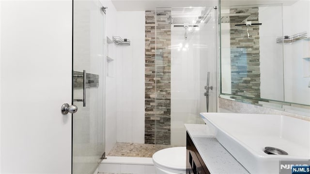 bathroom featuring vanity, an enclosed shower, and toilet