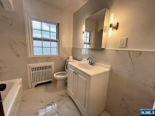 bathroom featuring vanity, toilet, radiator, and tile walls