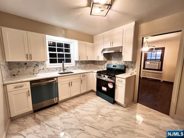 kitchen with white cabinetry, appliances with stainless steel finishes, sink, and radiator