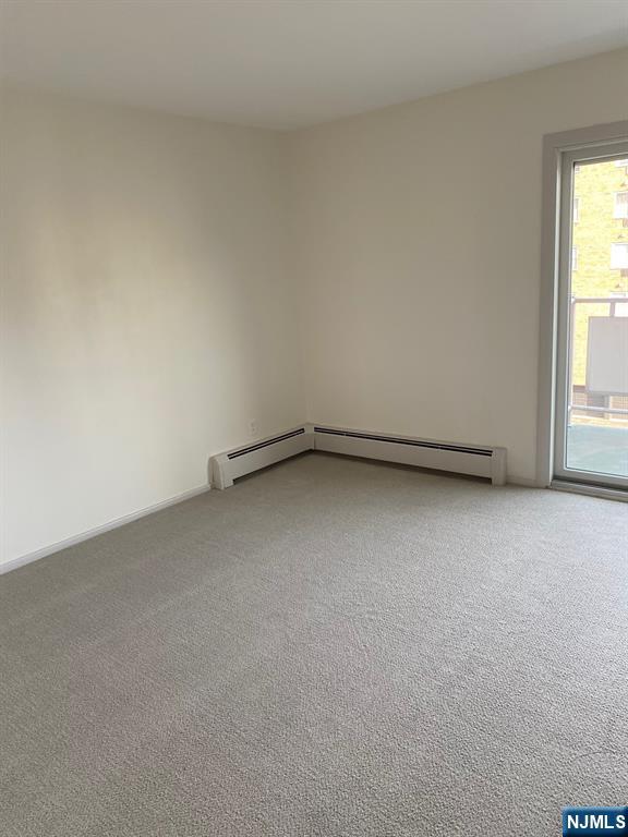 carpeted spare room featuring a baseboard radiator