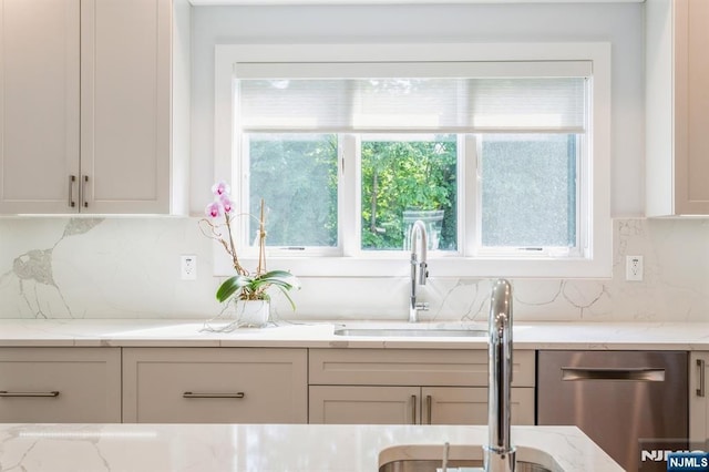 kitchen with tasteful backsplash, light stone countertops, and sink