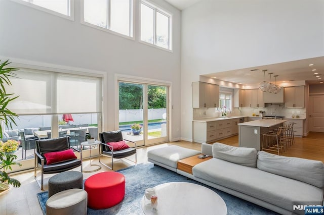 living room featuring sink, light wood-type flooring, and a towering ceiling