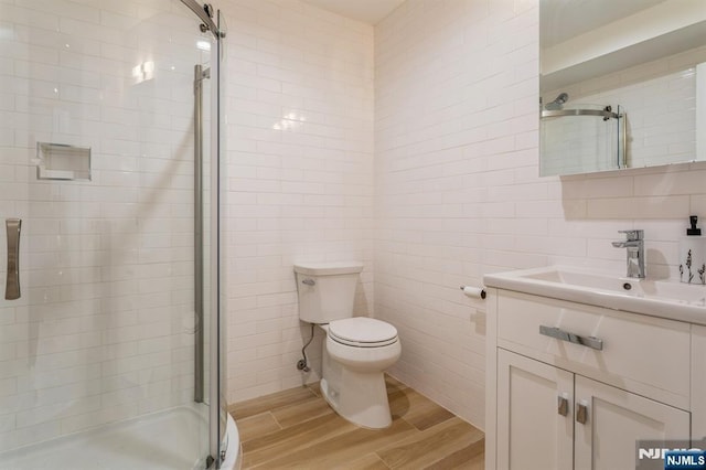 bathroom featuring tasteful backsplash, tile walls, vanity, toilet, and a shower with door