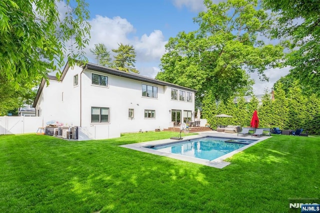 rear view of property with a pool side deck, a yard, and an outdoor living space