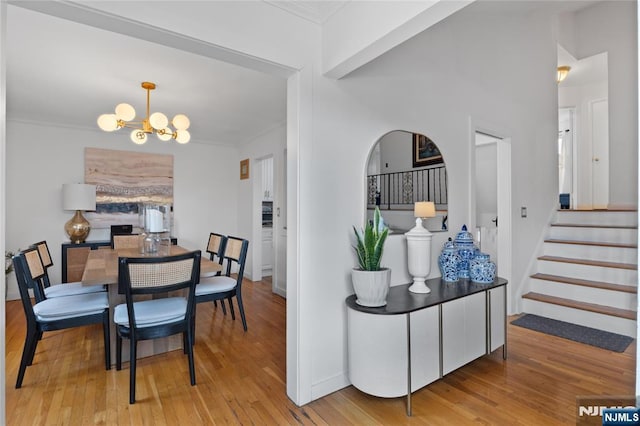 dining space with ornamental molding, a notable chandelier, and light wood-type flooring