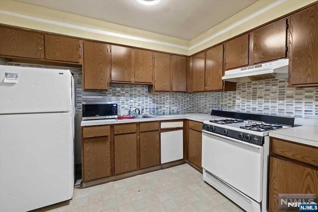 kitchen with sink, white appliances, and decorative backsplash