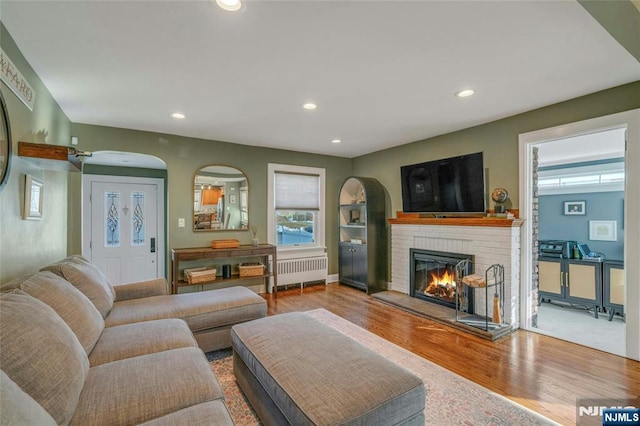 living room featuring hardwood / wood-style flooring, a fireplace, and radiator