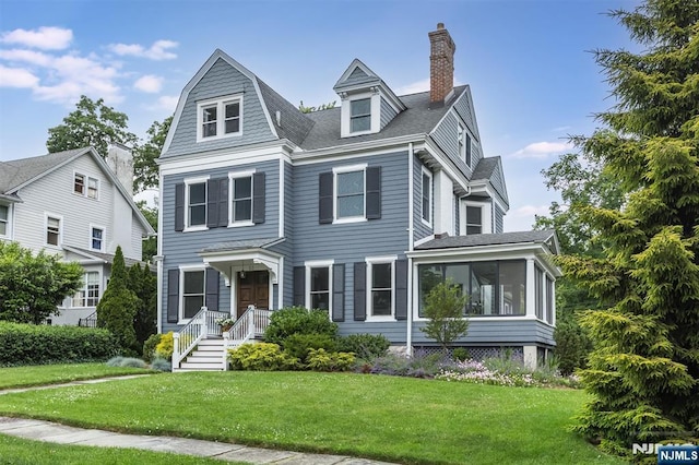 view of front of property featuring a sunroom and a front lawn