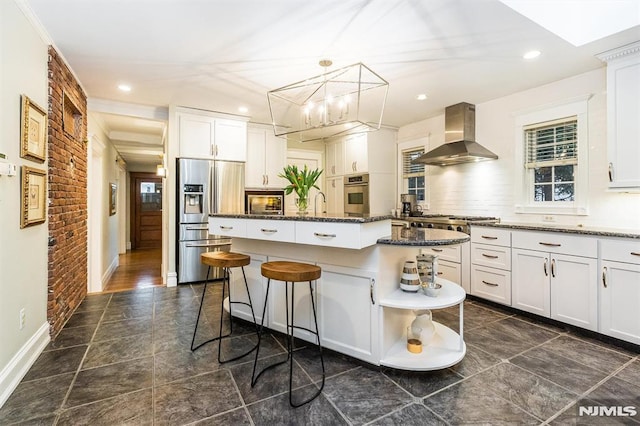 kitchen with extractor fan, appliances with stainless steel finishes, dark stone countertops, white cabinets, and a center island