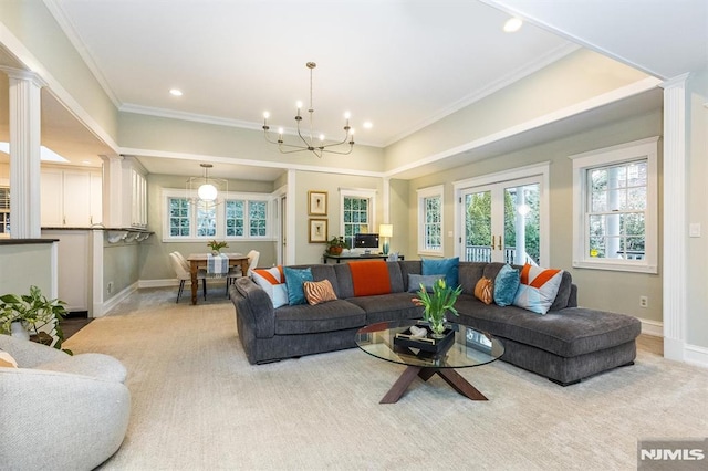 carpeted living room with a notable chandelier, crown molding, french doors, and ornate columns