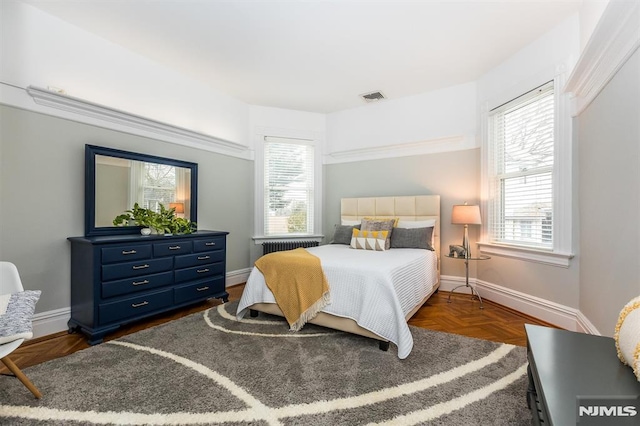 bedroom with multiple windows and dark parquet floors