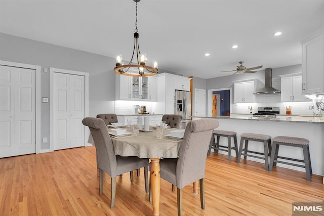 dining space with recessed lighting, ceiling fan with notable chandelier, and light wood finished floors