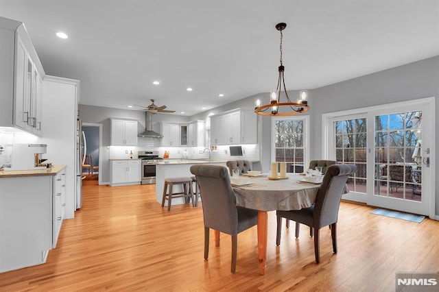 dining area with recessed lighting, light wood-style floors, and ceiling fan with notable chandelier