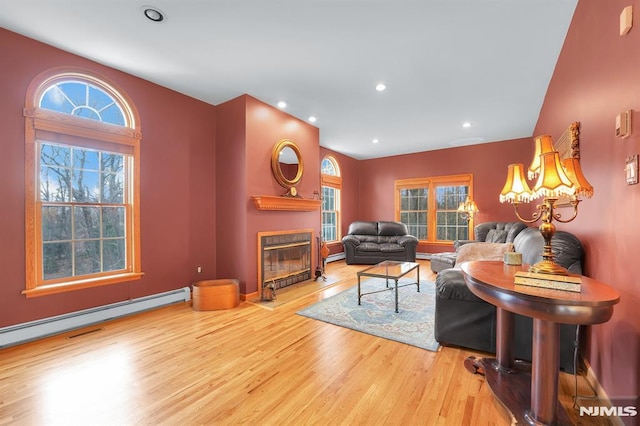 living room with a glass covered fireplace, recessed lighting, wood finished floors, and a baseboard radiator