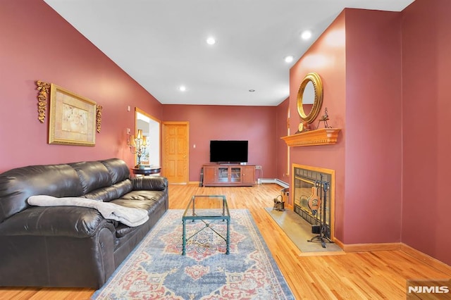 living area with a glass covered fireplace, recessed lighting, baseboards, and wood finished floors