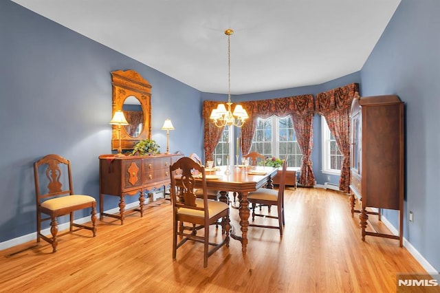 dining room with light wood-style flooring, baseboards, an inviting chandelier, and a baseboard radiator