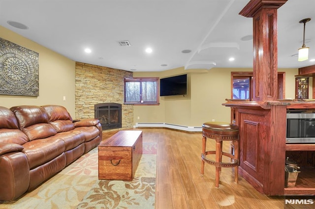 living room featuring visible vents, a baseboard heating unit, wood finished floors, recessed lighting, and a fireplace