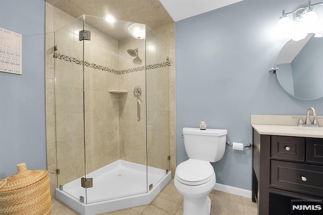 bathroom with vanity, baseboards, tile patterned flooring, a shower stall, and toilet